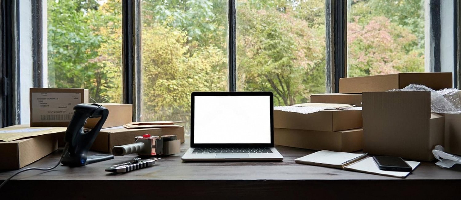 Laptop and shipping boxes on a supplier's desk, representing an online rental business in the UAE